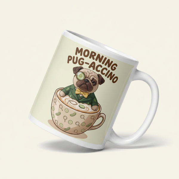 A funny graphic on a ceramic mug featuring Sir Cucumber Dog, a pug in a green suit and monocle, sitting inside a giant cappuccino cup. Text reads MORNING PUG-ACCINO.