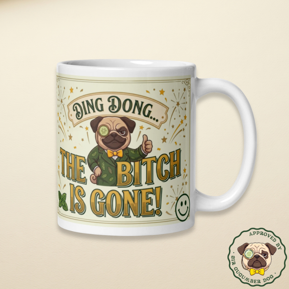 White glossy ceramic coffee mug featuring an illustration of Sir Cucumber Dog in a green suit with a monocle, giving a thumbs up, surrounded by gold starbursts and vintage text that reads Ding Dong The Bitch Is Gone!