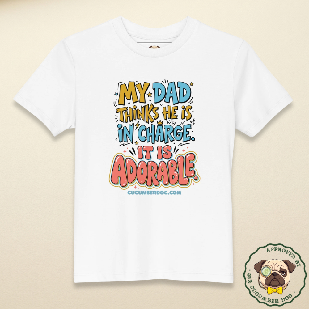 A white organic cotton children's t-shirt featuring colourful retro typography that reads: MY DAD THINKS HE IS IN CHARGE. IT IS ADORABLE. cucumberdog.com.