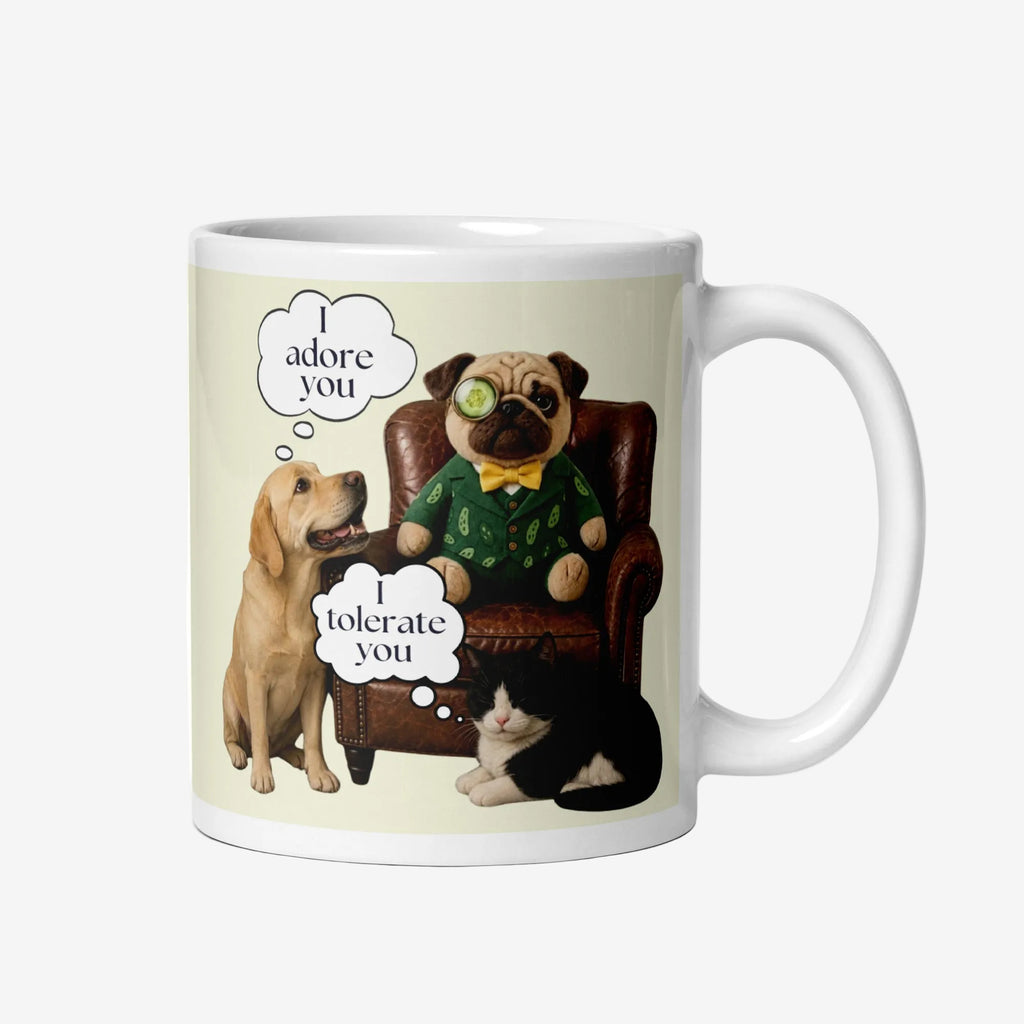 A premium cream ceramic mug featuring a happy golden retriever thinking I adore you, an indifferent black and white cat thinking I tolerate you, and Sir Cucumber Dog in a bespoke green suit judging them from a leather armchair.