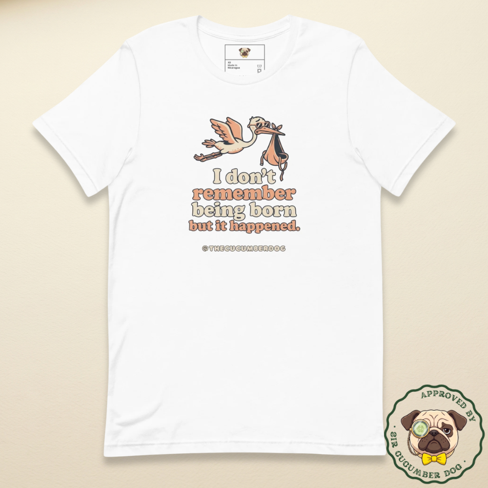 A white short-sleeve crewneck t-shirt featuring a graphic of a flying bird carrying a baby, with the text 'I don't remember being born but it happened.' in peach and brown lettering, displayed on a light beige background.