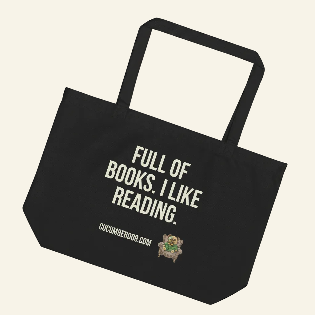 A heavyweight black organic cotton tote bag featuring bold Cucumber cream typography that reads: FULL OF BOOKS. I LIKE READING. The design includes the website URL CUCUMBERDOG.COM and an illustration of Sir Cucumber Dog—a plush pug in a dapper green cucumber-print suit and monocle—sitting regally in an ornate armchair.