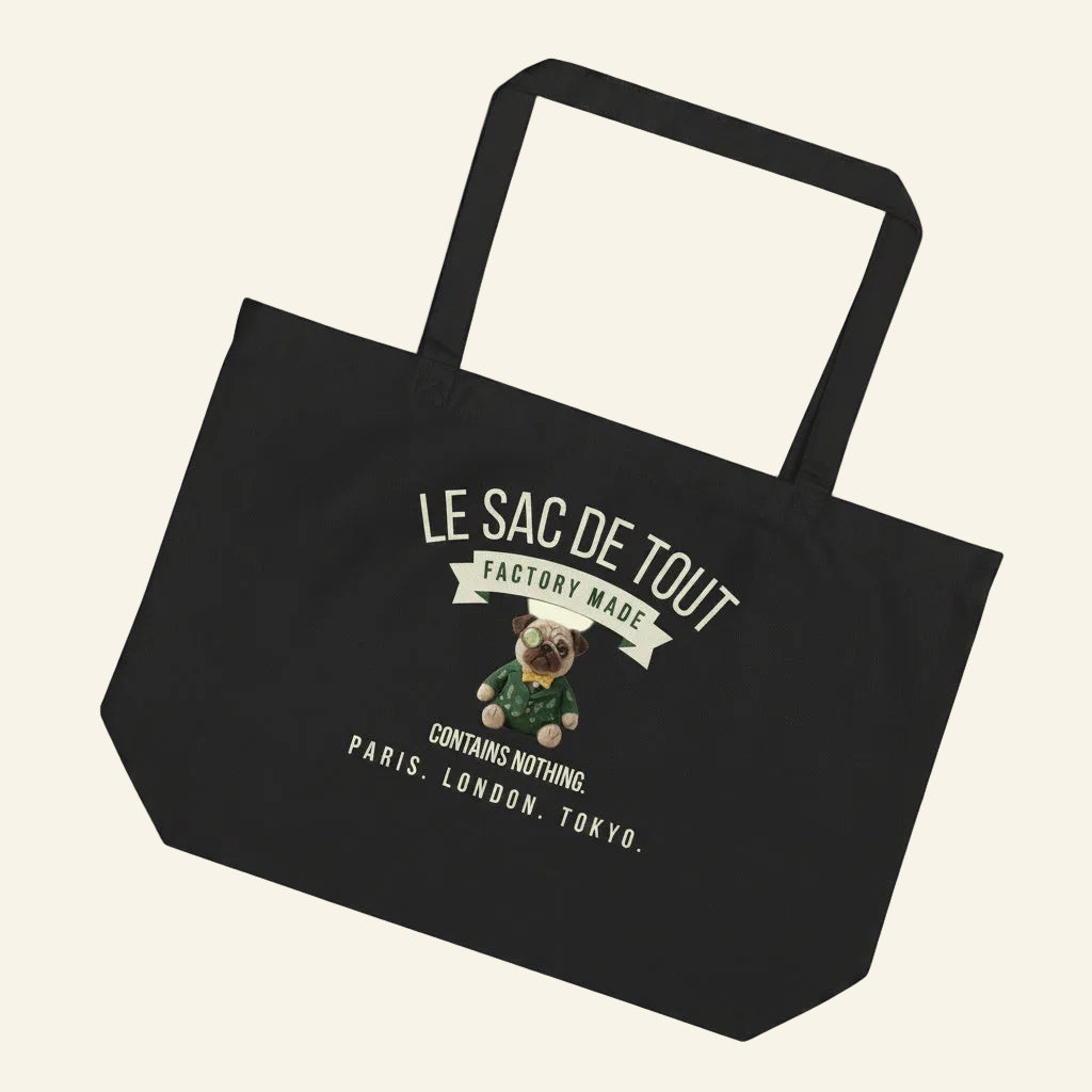 A heavy-duty deep black organic cotton tote bag. The front features text in a pale cream color: LE SAC DE TOUT over a cream banner reading FACTORY MADE. Below is a detailed illustration of a pug named Sir Cucumber Dog wearing a green suit, monocle, and bow tie, followed by the cream text CONTAINS NOTHING. PARIS. LONDON. TOKYO. The back displays the cream text CUCUMBERDOG.COM.