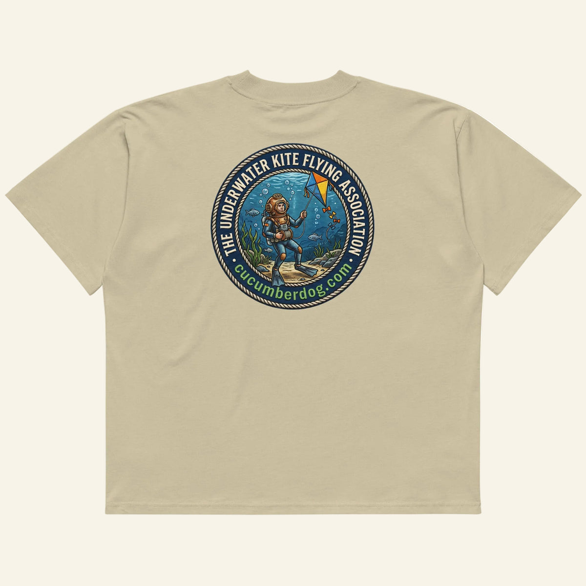 The back of a t-shirt featuring a circular nautical graphic. A vintage deep sea diver is underwater, attempting to fly a kite. The text reads The Underwater Kite Flying Association, cucumberdog.com in green lettering.