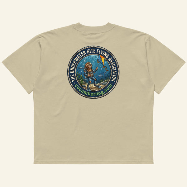 The back of a t-shirt featuring a circular nautical graphic. A vintage deep sea diver is underwater, attempting to fly a kite. The text reads The Underwater Kite Flying Association, cucumberdog.com in green lettering.