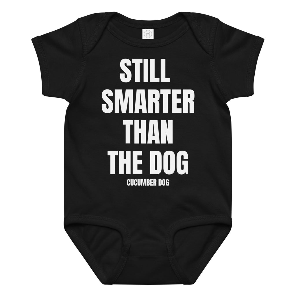 Black baby onesie with white text 'STILL SMARTER THAN THE DOG' and brand name Cucumber Dog on a white background
