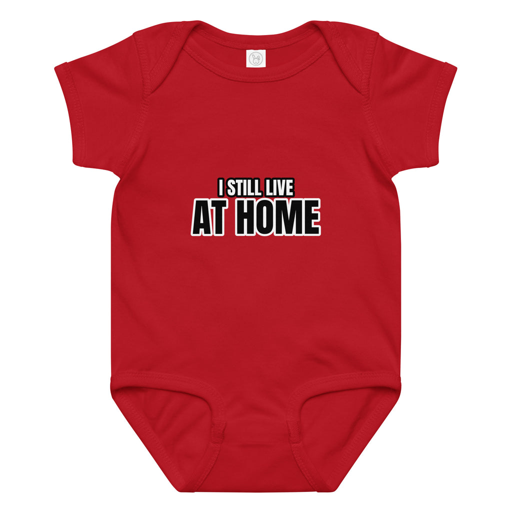 Red baby onesie with 'I STILL LIVE AT HOME' text on a white background. Cucumber Dog