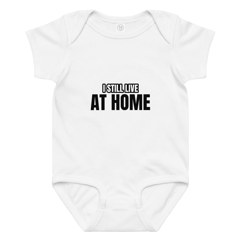 White baby onesie with 'I STILL LIVE AT HOME' text on a white background. Cucumber Dog