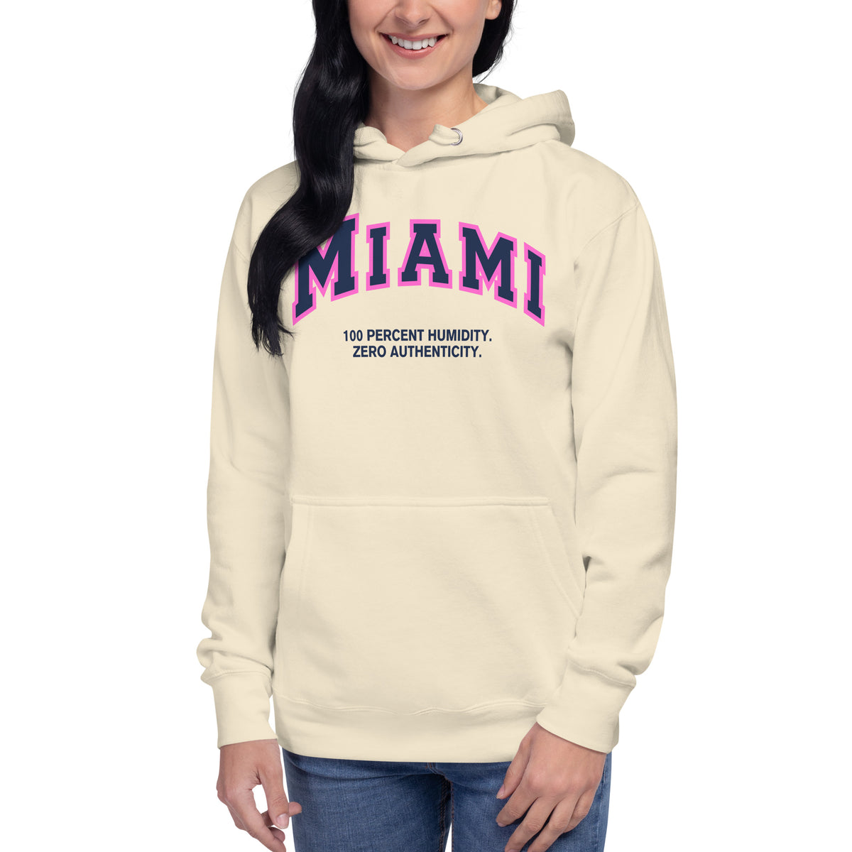 Premium bone coloured hoodie featuring a vintage athletic graphic with arched Miami text in dark blue and pink, and the phrase 100 Percent Humidity Zero Authenticity printed underneath in a solid black serif font.