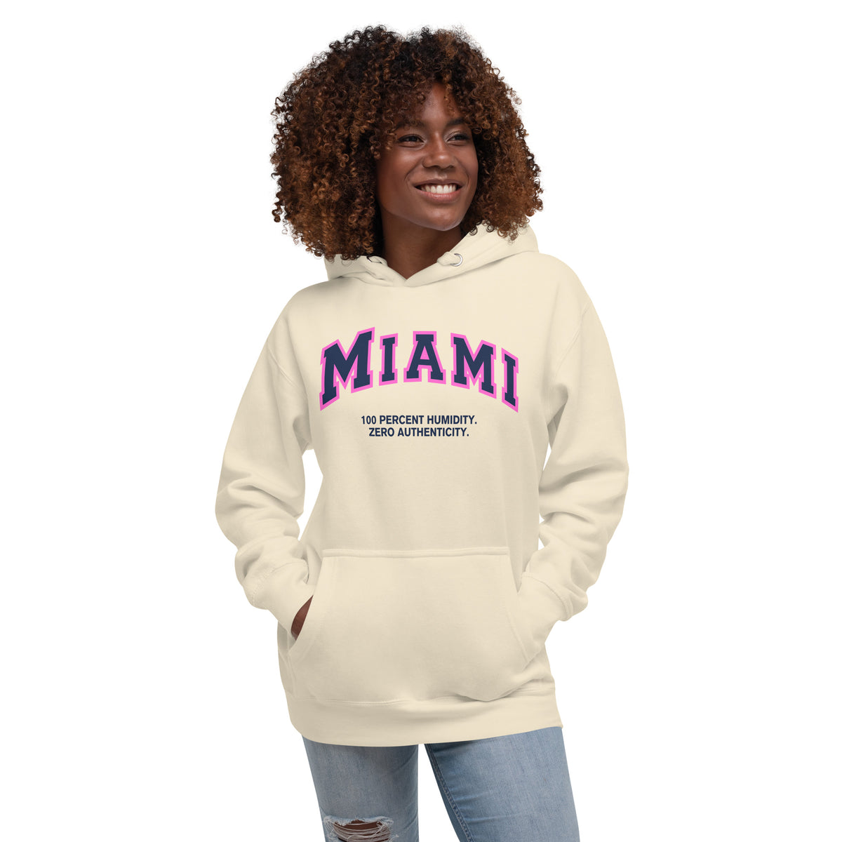 Premium bone coloured hoodie featuring a vintage athletic graphic with arched Miami text in dark blue and pink, and the phrase 100 Percent Humidity Zero Authenticity printed underneath in a solid black serif font.