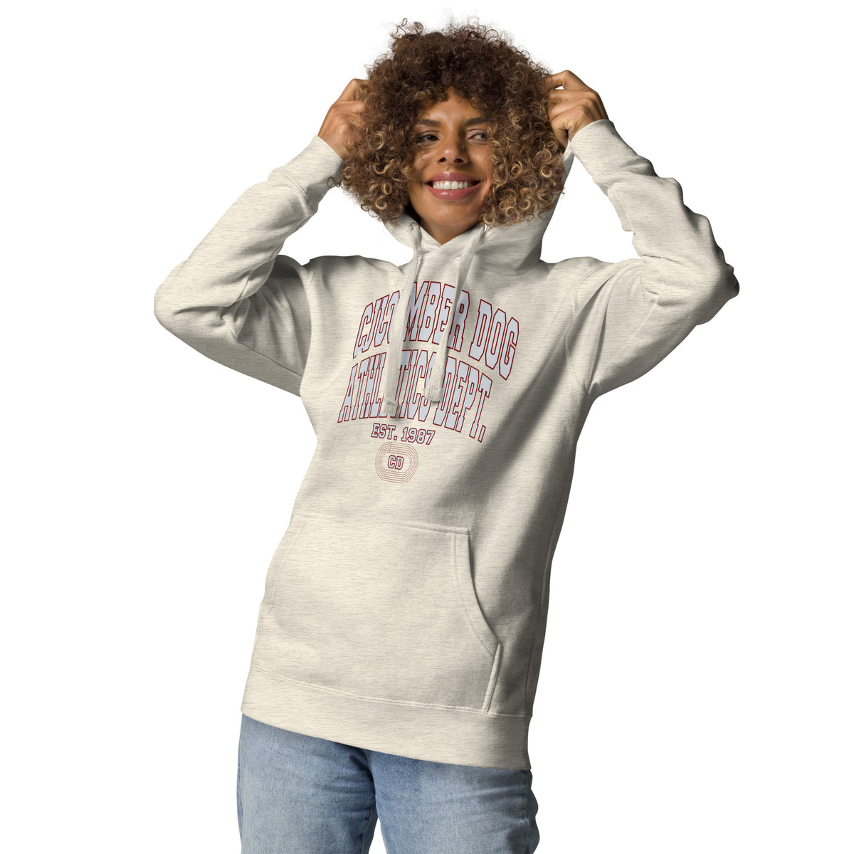 Premium oatmeal heather hoodie featuring a vintage athletic graphic with arched Cucumber Dog and Athletics Dept text in grey block typography with a maroon outline, above Est. 1987 and a track motif framing the CD monogram.