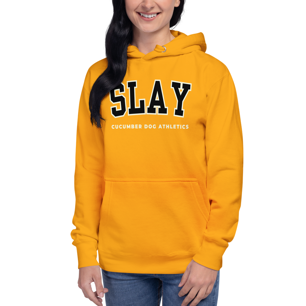 A woman wearing a bright gold pullover hoodie with 'SLAY' in black varsity letters outlined in white, and 'CUCUMBER DOG ATHLETICS' printed below, against a plain white background.