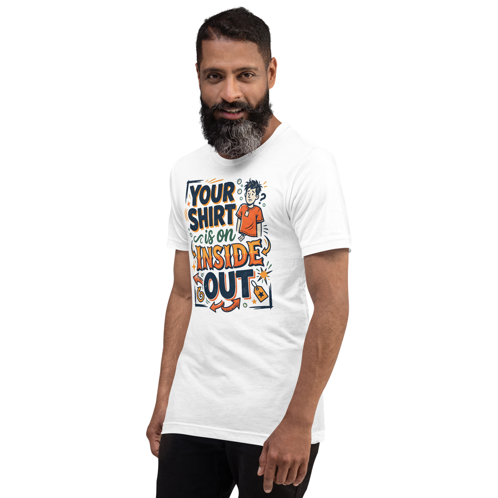 Person wearing a white unisex t-shirt featuring a cartoon illustration of a confused man with an exposed clothing tag, surrounded by bold retro typography that reads: YOUR SHIRT IS ON INSIDE OUT.