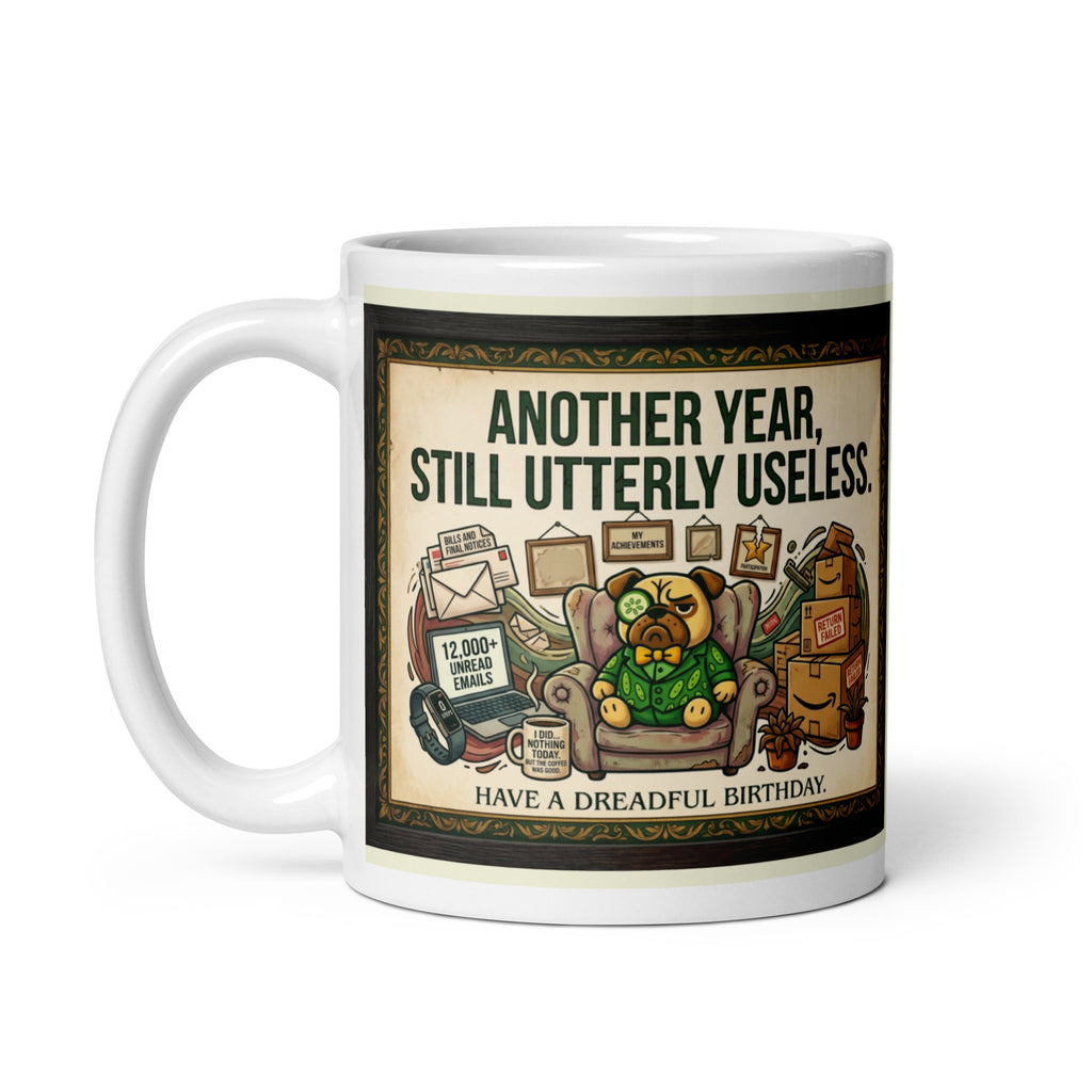 White glossy mug featuring Sir Cucumber Dog the pug. The text "ANOTHER YEAR... STILL UTTERLY USELESS." is rendered in Cucumber green. Cucumber Dog. 