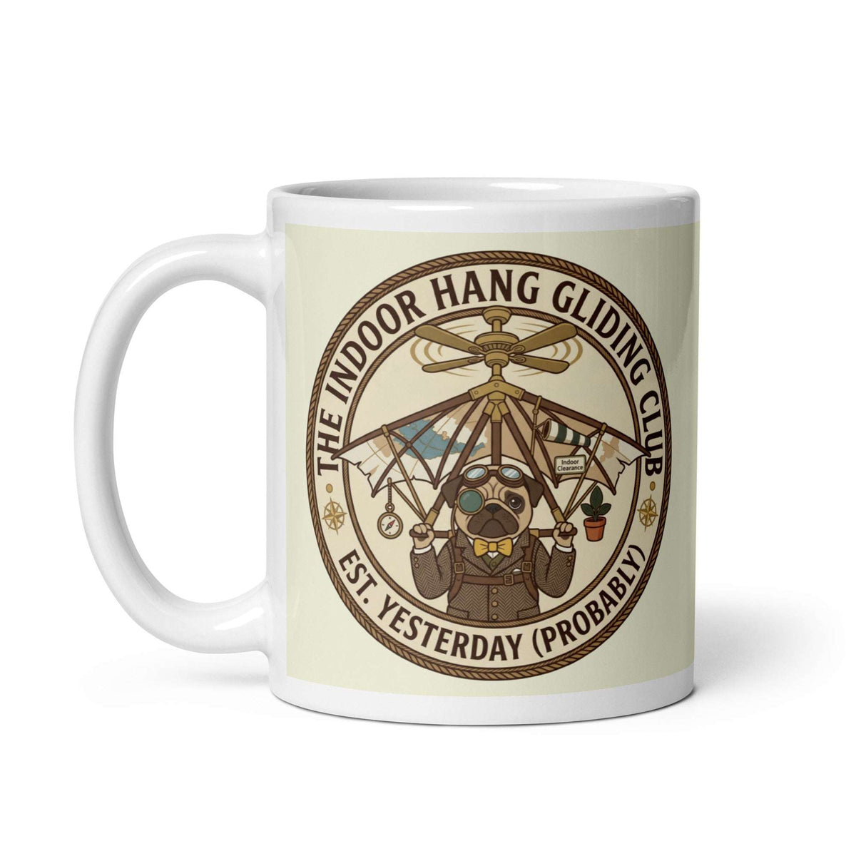 A circular vintage emblem on a transparent background. It reads THE INDOOR HANG GLIDING CLUB EST. YESTERDAY (PROBABLY). Inside, Sir Cucumber Dog wears a tweed suit and aviator goggles, strapped to a hang glider that is attached to a ceiling fan. 11 oz