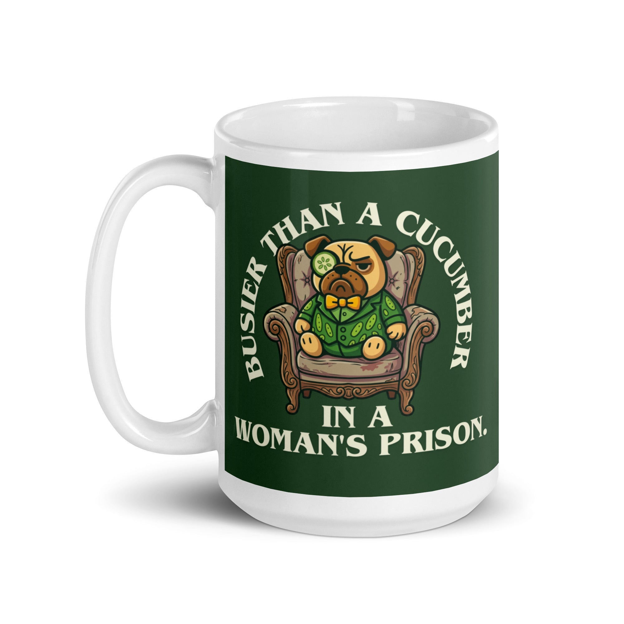 A tilted white ceramic mug with a large dark green label. In the centre of the label, a pug named Sir Cucumber Dog sits in an armchair wearing a cucumber suit and monocle. The white text reads BUSIER THAN A CUCUMBER IN A WOMAN S PRISON. 15oz
