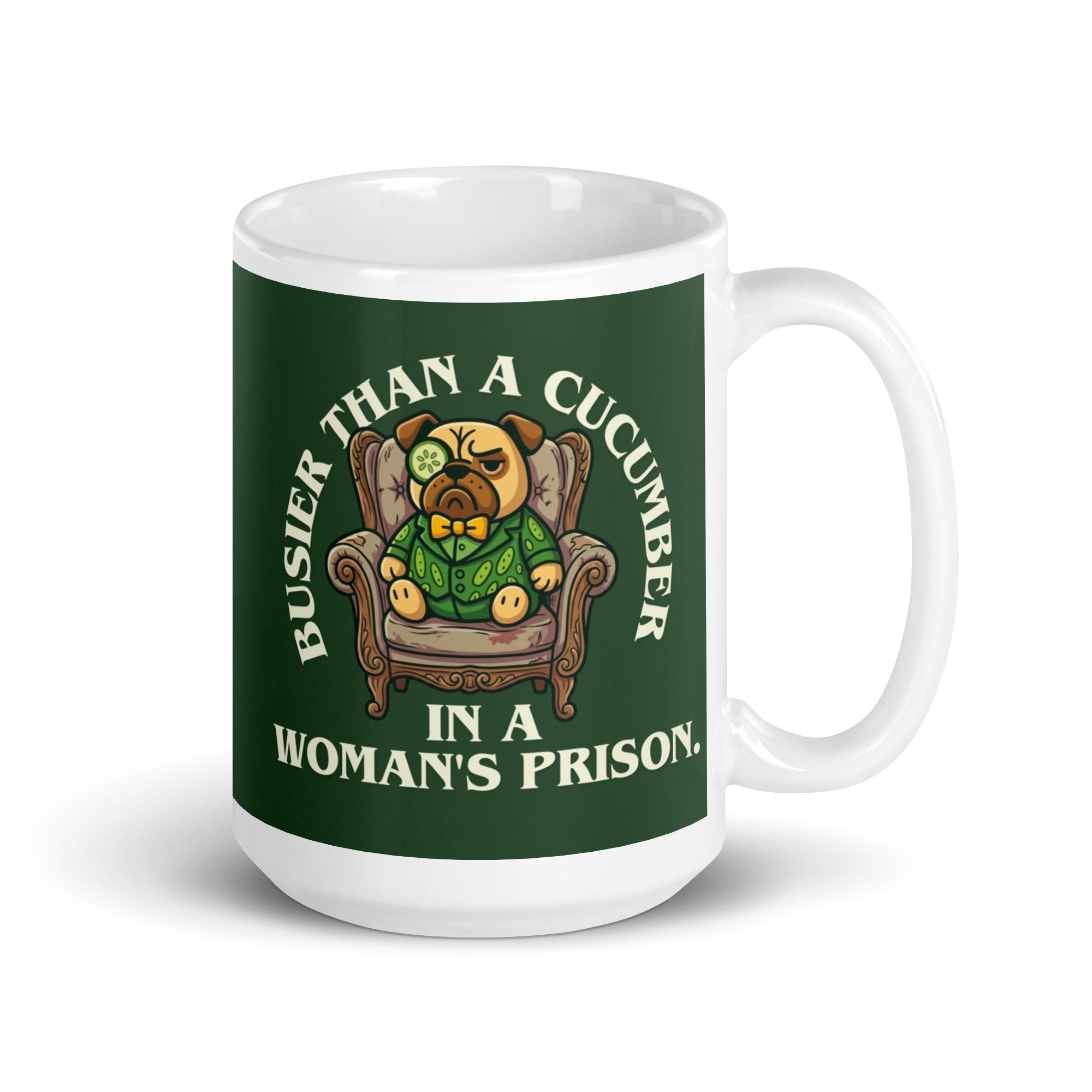 A tilted white ceramic mug with a large dark green label. In the centre of the label, a pug named Sir Cucumber Dog sits in an armchair wearing a cucumber suit and monocle. The white text reads BUSIER THAN A CUCUMBER IN A WOMAN S PRISON. 15oz
